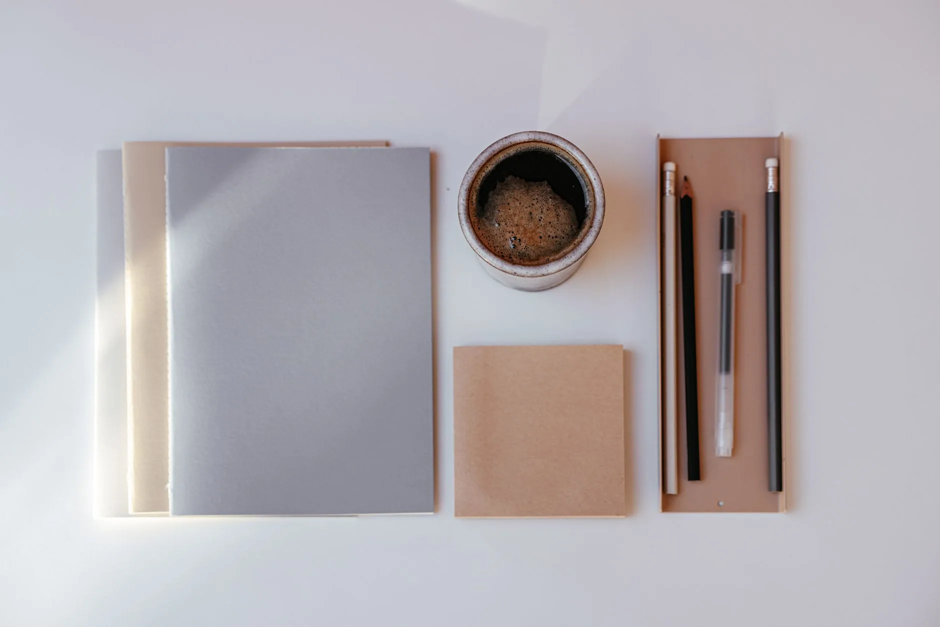 Desk with notebook, pen, and laptop, demonstrating Oxford comma usage, muted lighting.